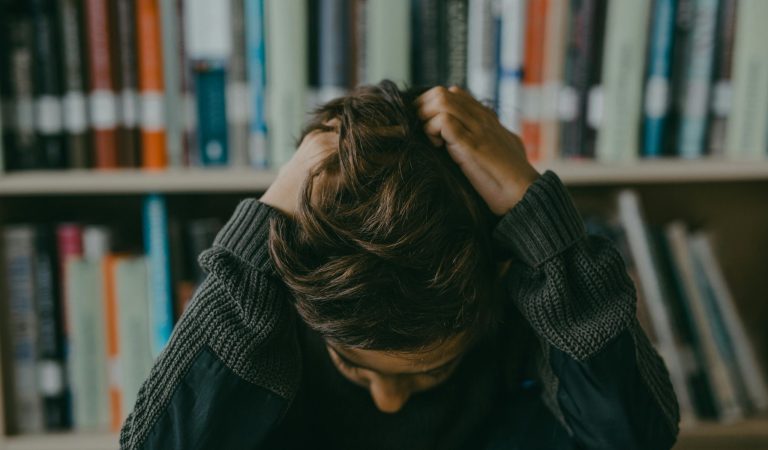 IGCSE student revising challenging subjects with notes and laptop