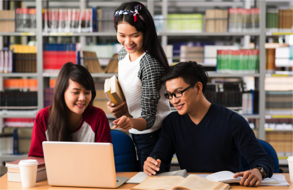 group-of-asian-students-studying-in-library-while-girl-points-at-screen-holding-books